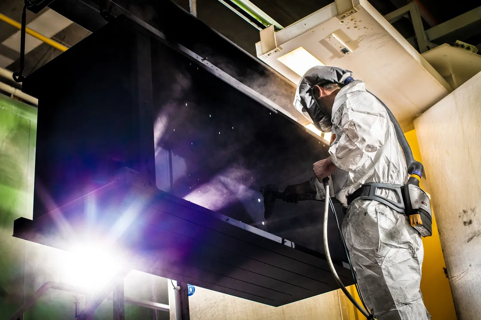 Licht und Handwerk Lackierer bei der Pulverbeschichtung im Maschinenbau, Industriefoto für ABW Metalltechnik in Hockenheim