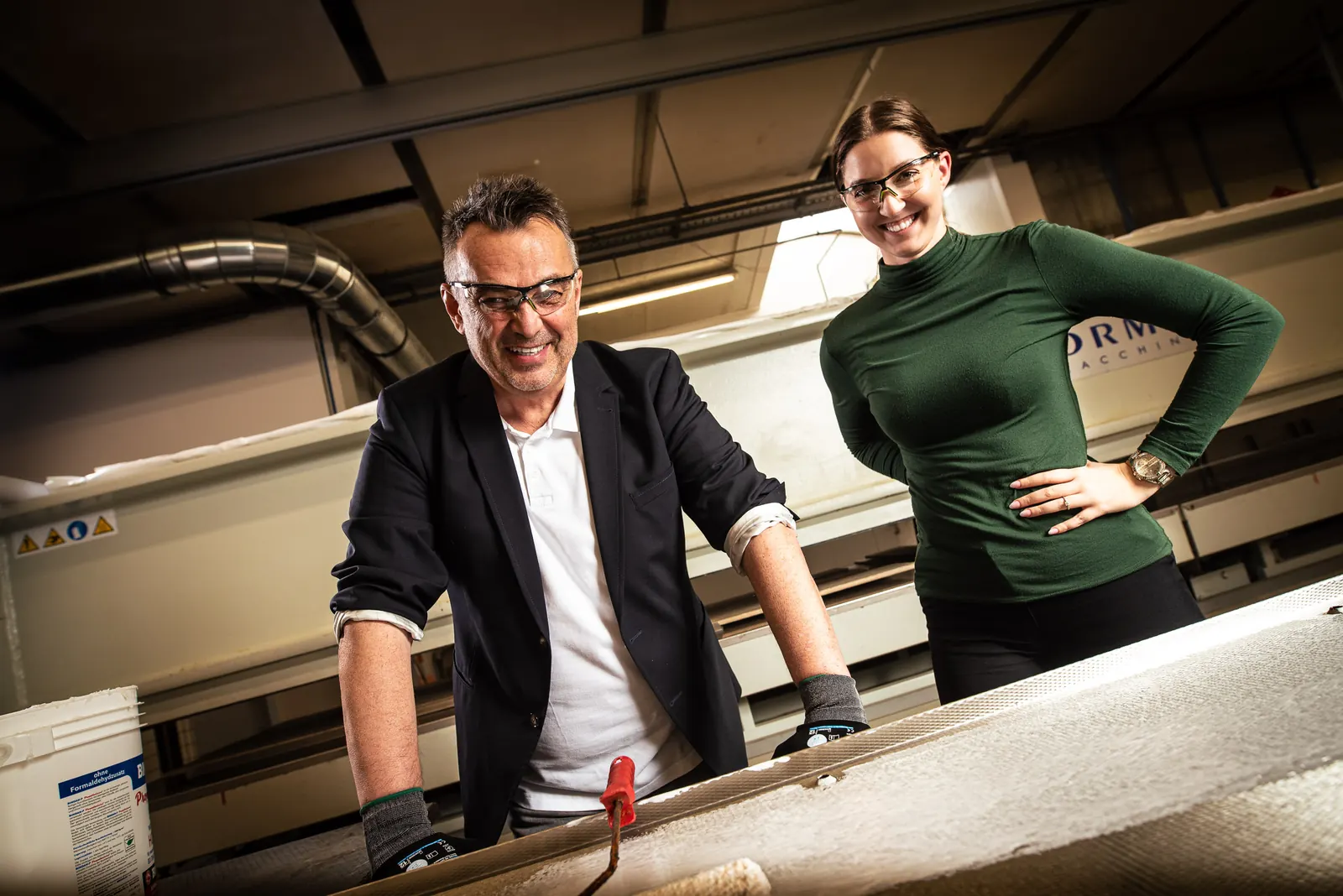 Team mit Haltung Uwe Narr zeigt einer Auszubildenden einen Arbeitsschritt in der Produktion, Imagefoto für NARR Isoliersysteme